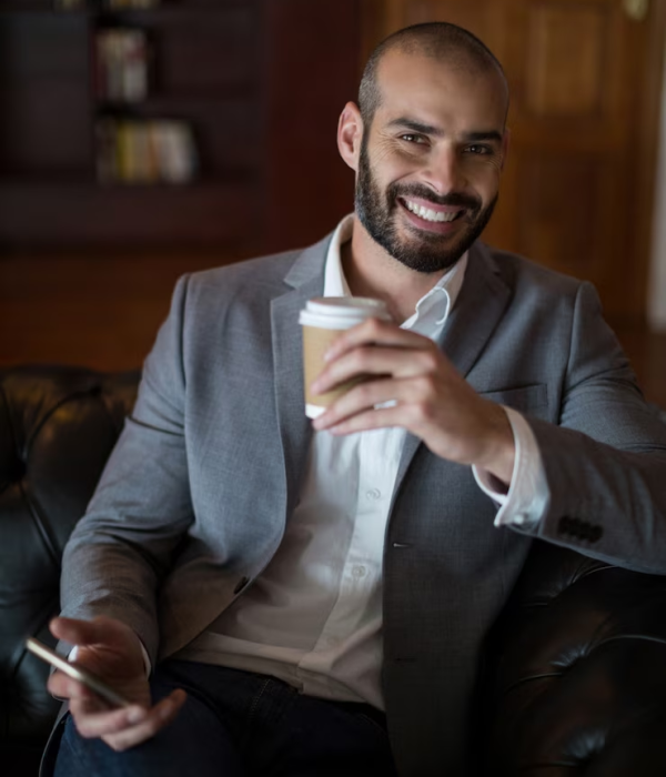 portrait-smiling-businessman-holding-mobile-phone-coffee-cup-waiting-area_107420-95820